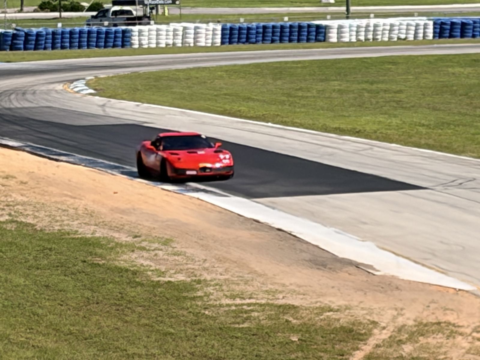 Red sports car turning through a corner with dark rubber marks on the track